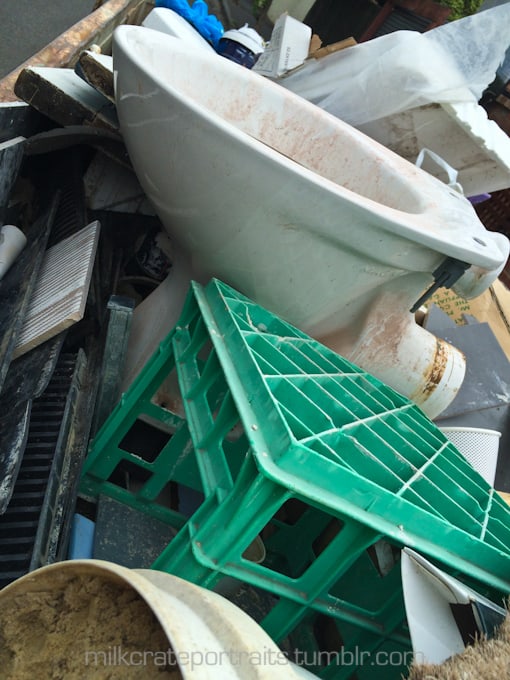 Toilet and milk crate in the dumpster
